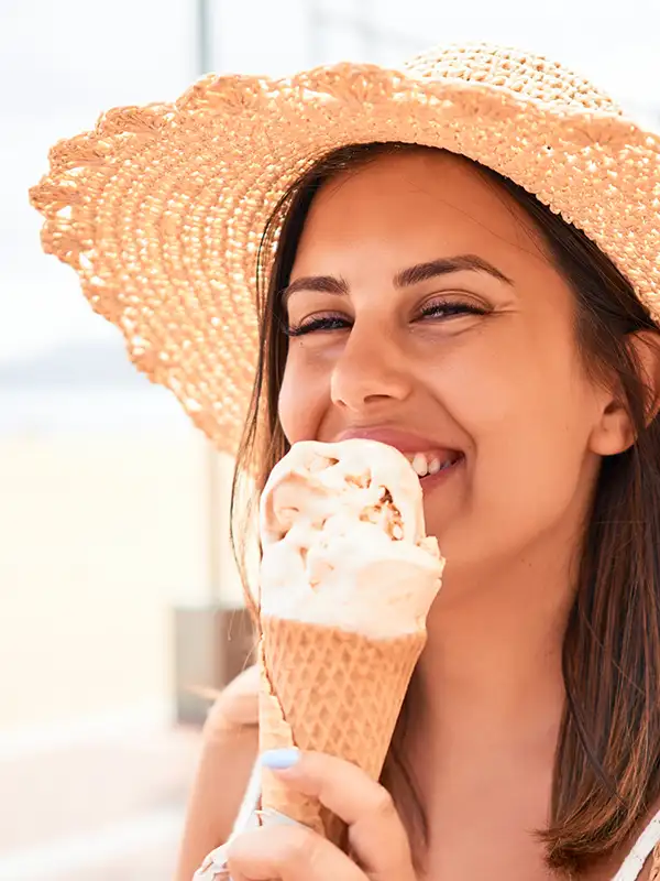 Eine junge Frau läuft entlang einer Strandpromenade und genießt ein Eis